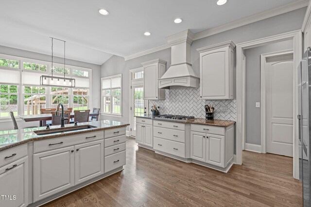 204 Franconia Way, Apex, NC 27502 - kitchen featuring stainless steel gas stovetop, vaulted ceiling, white cabinetry, decorative backsplash, and premium range hood