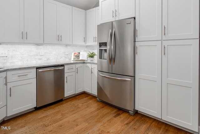 123 Becket Bnd, Pittsboro, NC 27312 - kitchen with stainless steel appliances, white cabinetry, light wood-style flooring, tasteful backsplash, and light stone counters