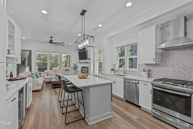 415 1st St, Apex, NC 27502 - kitchen featuring stainless steel appliances, wall chimney exhaust hood, a sink, open floor plan, and light countertops