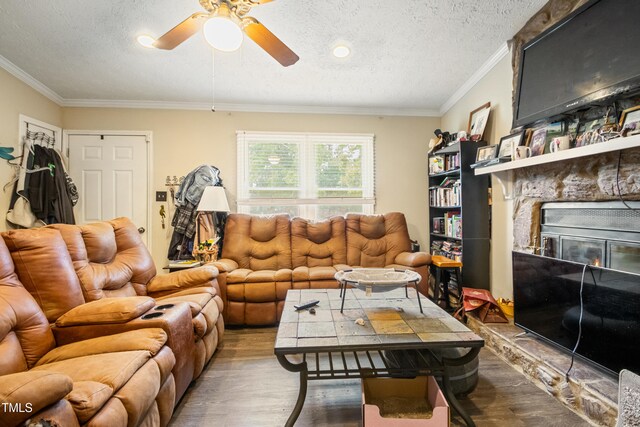 6424 Bretton Woods Dr, Hope Mills, NC 28348 - living room with wood finished floors, a stone fireplace, ceiling fan, crown molding, and a textured ceiling