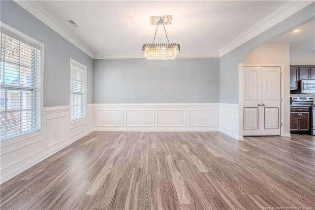 2912 Seafarer Dr, Fayetteville, NC 28306 - unfurnished dining area featuring wood finished floors, wainscoting, a chandelier, ornamental molding, and arched walkways