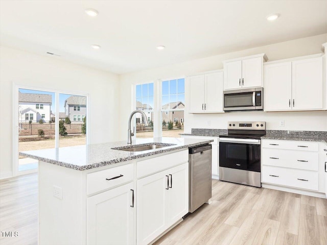425 Hipwood Dr, Zebulon, NC 27597 - kitchen featuring stainless steel appliances, a sink, an island with sink, light stone counters, and light wood-style flooring