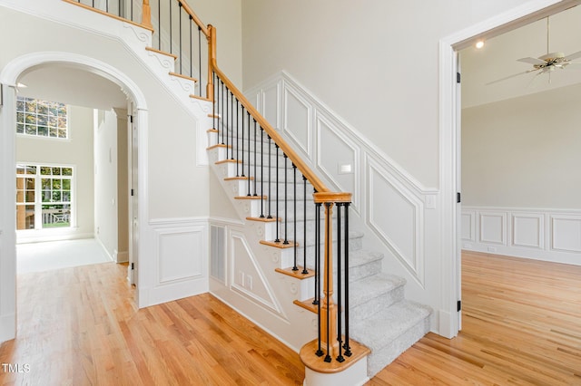6553 Vintage Ridge Ln, Fuquay Varina, NC 27526 - stairway featuring wood finished floors, arched walkways, a decorative wall, a high ceiling, and wainscoting