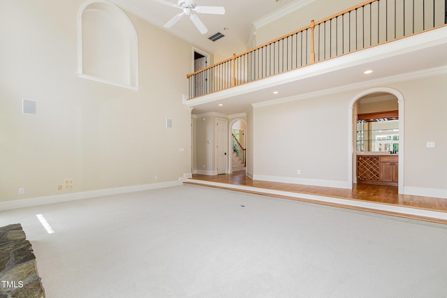 6553 Vintage Ridge Ln, Fuquay Varina, NC 27526 - unfurnished living room featuring crown molding, arched walkways, a towering ceiling, ceiling fan, and carpet