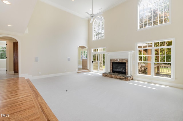 6553 Vintage Ridge Ln, Fuquay Varina, NC 27526 - unfurnished living room featuring arched walkways, a high ceiling, a stone fireplace, baseboards, and ceiling fan