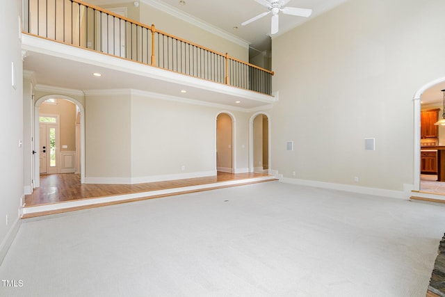 6553 Vintage Ridge Ln, Fuquay Varina, NC 27526 - unfurnished living room featuring arched walkways, a towering ceiling, a ceiling fan, ornamental molding, and carpet