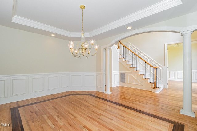 6553 Vintage Ridge Ln, Fuquay Varina, NC 27526 - unfurnished dining area featuring wood finished floors, decorative columns, a decorative wall, arched walkways, and ornamental molding