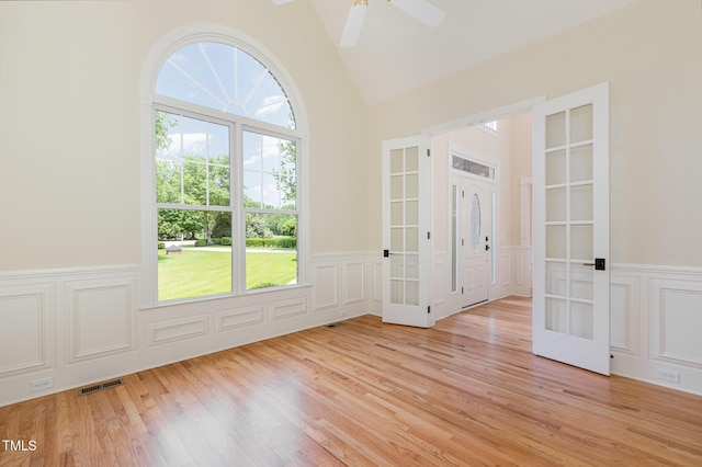 6553 Vintage Ridge Ln, Fuquay Varina, NC 27526 - unfurnished room featuring french doors, a decorative wall, wainscoting, lofted ceiling, and light wood-type flooring