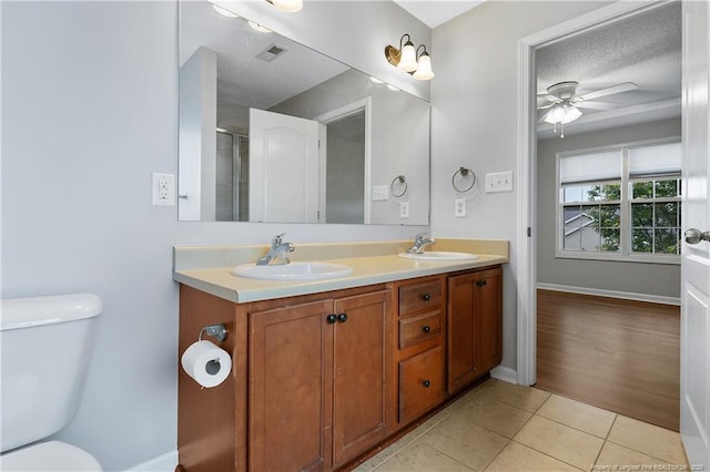 4420 Battle Forest Rd, Hope Mills, NC 28348 - full bathroom featuring double vanity, toilet, tile patterned floors, a ceiling fan, and an enclosed shower