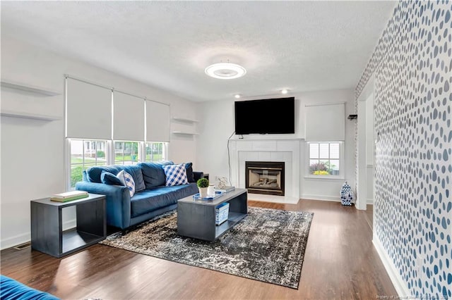 1502 E 11th St, Lumberton, NC 28358 - living room with healthy amount of natural light, wood finished floors, a textured ceiling, wallpapered walls, and a tile fireplace