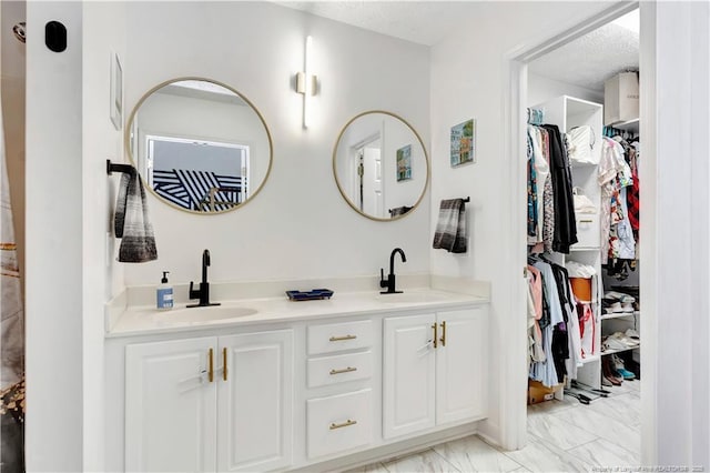 1502 E 11th St, Lumberton, NC 28358 - full bathroom featuring double vanity, a textured ceiling, a spacious closet, and marble finish flooring