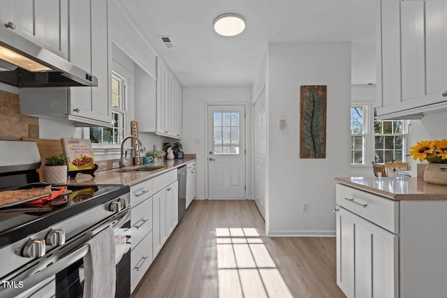 1536 Maybrook Dr, Raleigh, NC 27610 - kitchen with appliances with stainless steel finishes, range hood, a sink, light wood finished floors, and light countertops