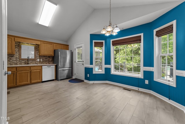 1383 Deercroft Ct, Graham, NC 27253 - kitchen featuring freestanding refrigerator, white dishwasher, brown cabinetry, vaulted ceiling, and a chandelier