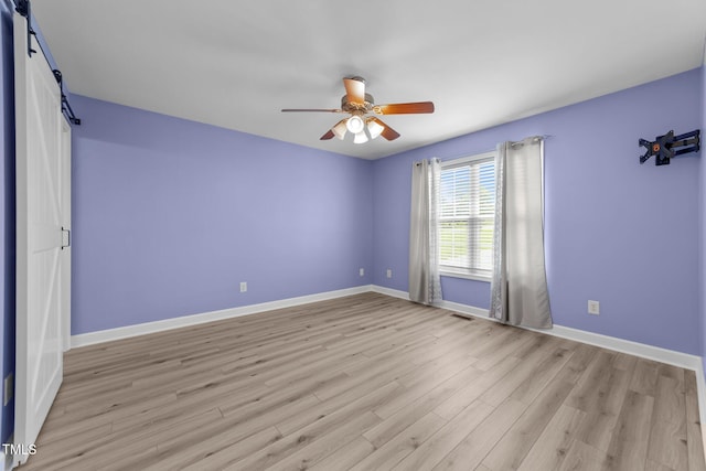 1383 Deercroft Ct, Graham, NC 27253 - empty room featuring a barn door, a ceiling fan, baseboards, and light wood-style floors