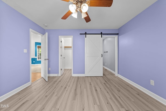 1383 Deercroft Ct, Graham, NC 27253 - unfurnished bedroom featuring baseboards, a barn door, light wood finished floors, a spacious closet, and a closet