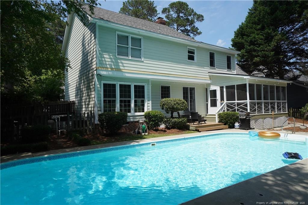 2963 Delaware Dr, Fayetteville, NC 28304 - back of house featuring a sunroom, an outdoor pool, a chimney, a deck, and roof with shingles