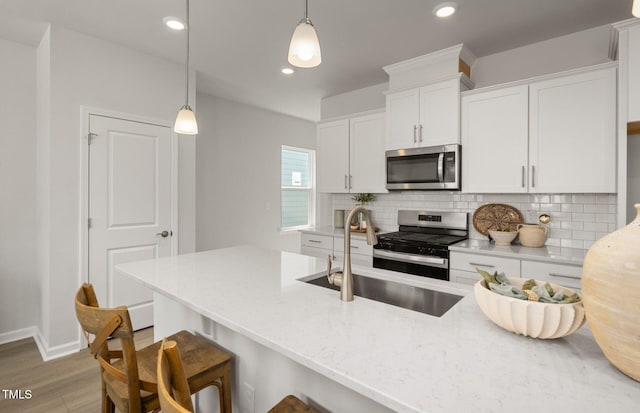 1525 Tamarisk Ln, Durham, NC 27703 - kitchen featuring stainless steel appliances, decorative backsplash, white cabinets, light wood-style floors, and decorative light fixtures
