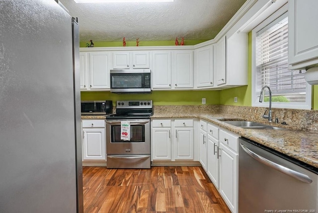 1314 Four Wood Dr, Fayetteville, NC 28312 - kitchen with stainless steel appliances, a sink, white cabinetry, dark wood-type flooring, and a textured ceiling