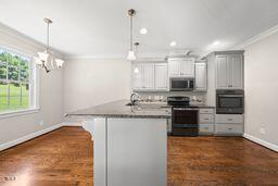 311 Rassie Crabtree Rd, Rougemont, NC 27572 - kitchen featuring appliances with stainless steel finishes, crown molding, decorative light fixtures, a chandelier, and dark wood-style flooring
