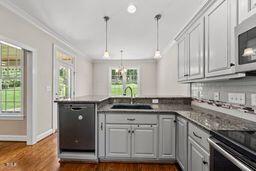 311 Rassie Crabtree Rd, Rougemont, NC 27572 - kitchen featuring a peninsula, crown molding, dark wood-style flooring, pendant lighting, and stainless steel appliances
