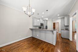 311 Rassie Crabtree Rd, Rougemont, NC 27572 - kitchen with a peninsula, a chandelier, dark wood-style floors, crown molding, and recessed lighting
