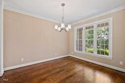 311 Rassie Crabtree Rd, Rougemont, NC 27572 - empty room with ornamental molding, a chandelier, and dark wood-type flooring