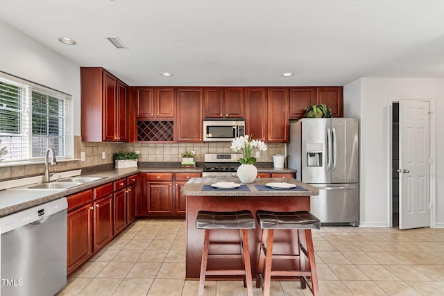 518 Emerald Downs Rd, Cary, NC 27519 - kitchen with stainless steel appliances, light tile patterned floors, decorative backsplash, reddish brown cabinets, and a center island