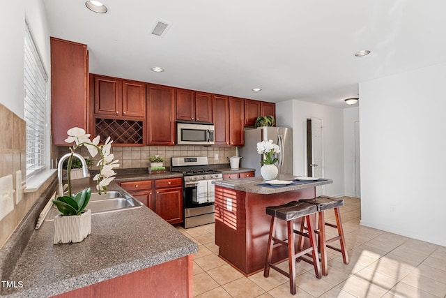 518 Emerald Downs Rd, Cary, NC 27519 - kitchen with stainless steel appliances, a breakfast bar, tasteful backsplash, a kitchen island, and light tile patterned floors