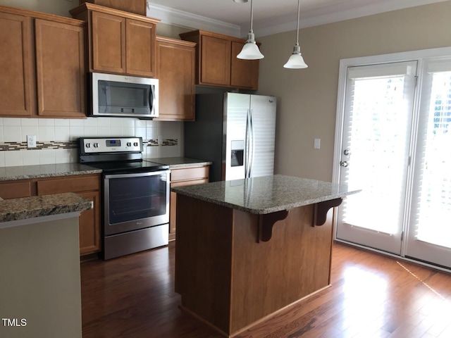 115 Ballyliffen Ln, Cary, NC 27519 - kitchen with stainless steel appliances, dark wood-type flooring, brown cabinetry, a kitchen island, and tasteful backsplash