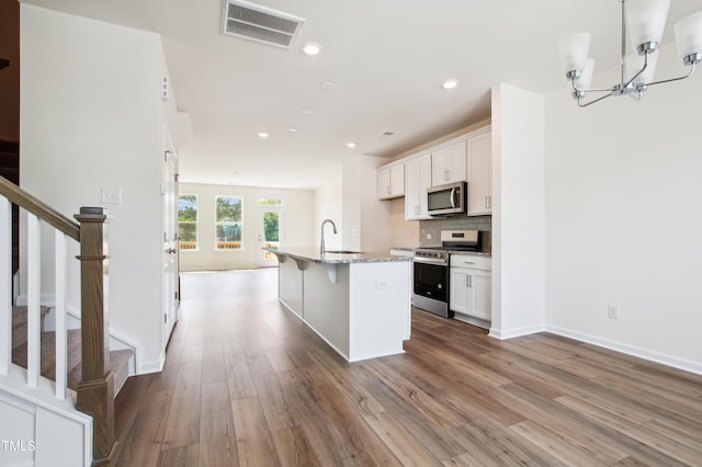 744 Parc Townes Dr Unit 34, Wendell, NC 27591 - kitchen featuring appliances with stainless steel finishes, wood finished floors, a kitchen island with sink, white cabinets, and a sink