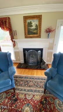 3409 Bennyfield Ct, Fuquay Varina, NC 27526 - living room featuring a glass covered fireplace, wood finished floors, crown molding, and a wainscoted wall