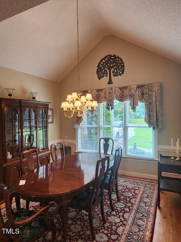 3409 Bennyfield Ct, Fuquay Varina, NC 27526 - dining area with a textured ceiling, vaulted ceiling, wood finished floors, and a chandelier