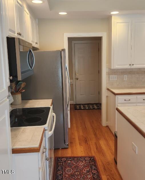 3409 Bennyfield Ct, Fuquay Varina, NC 27526 - kitchen featuring stainless steel microwave, white electric stove, white cabinets, light wood-style floors, and recessed lighting
