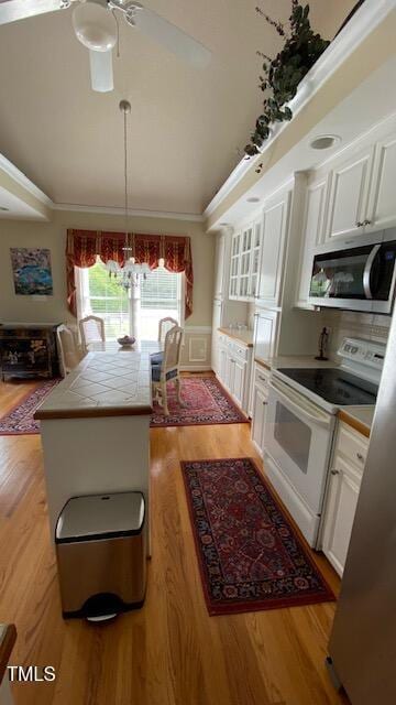 3409 Bennyfield Ct, Fuquay Varina, NC 27526 - kitchen with white electric range oven, stainless steel microwave, tile counters, light wood-style floors, and white cabinetry