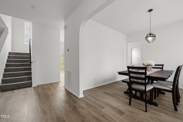 5332 Seaspray Ln, Raleigh, NC 27610 - dining space featuring arched walkways, stairway, wood finished floors, and baseboards