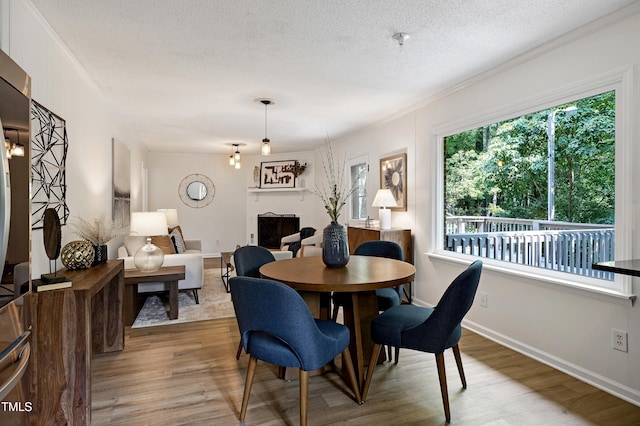 1416 Bramble Dr, Durham, NC 27712 - dining area with wood finished floors, a textured ceiling, crown molding, a fireplace, and baseboards