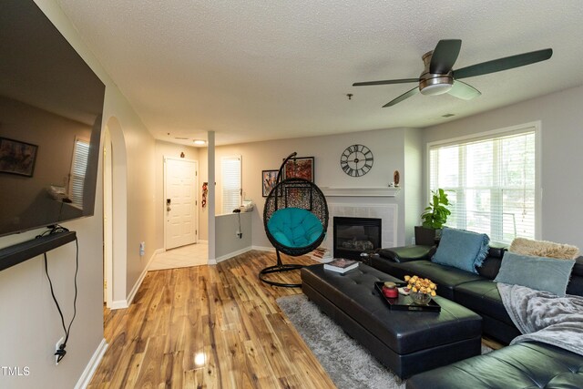 1911 Falls Landing Dr Unit 103, Raleigh, NC 27614 - living area with a tile fireplace, baseboards, arched walkways, ceiling fan, and a textured ceiling