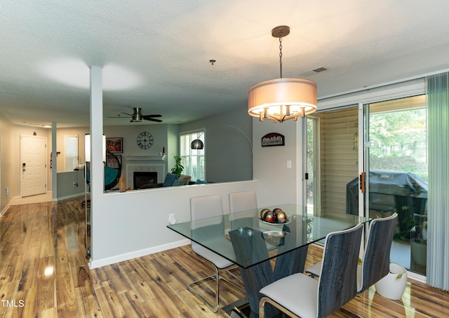1911 Falls Landing Dr Unit 103, Raleigh, NC 27614 - dining area with a fireplace, ceiling fan, wood finished floors, baseboards, and a chandelier