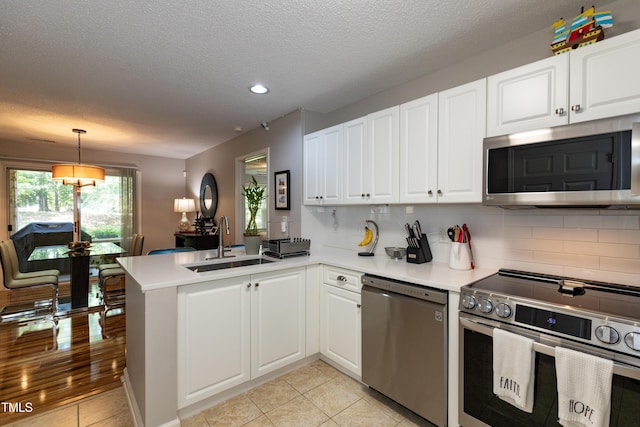 1911 Falls Landing Dr Unit 103, Raleigh, NC 27614 - kitchen with appliances with stainless steel finishes, a sink, a peninsula, decorative backsplash, and white cabinets