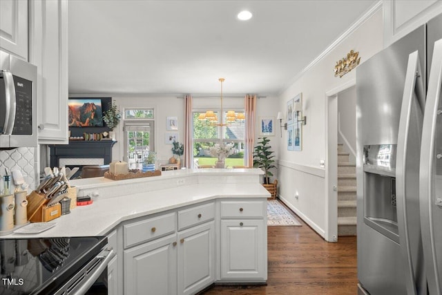 817 Mossy Oak Dr, Fuquay Varina, NC 27526 - kitchen featuring stainless steel appliances, a peninsula, white cabinetry, dark wood finished floors, and ornamental molding
