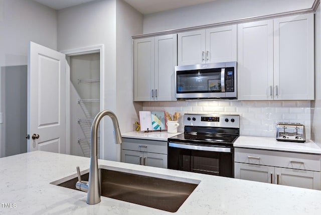 1227 Bessie Ct, Wake Forest, NC 27587 - kitchen with stainless steel appliances, gray cabinetry, a sink, and backsplash