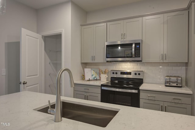 1227 Bessie Ct, Wake Forest, NC 27587 - kitchen featuring appliances with stainless steel finishes, gray cabinets, a sink, and light stone countertops
