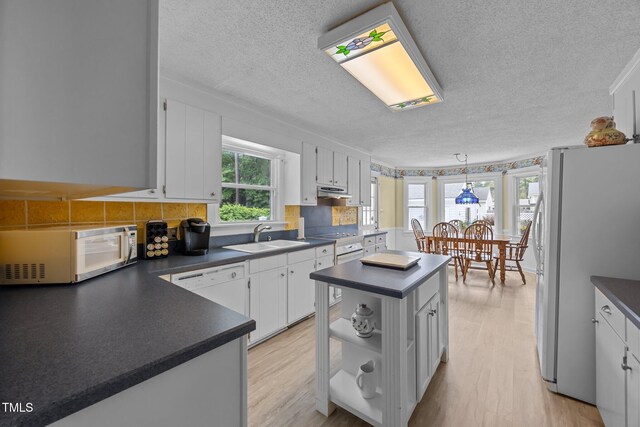 2000 Glissom St, Tarboro, NC 27886 - kitchen with white appliances, dark countertops, a textured ceiling, a center island, and white cabinetry