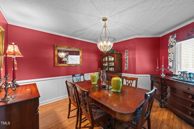 2000 Glissom St, Tarboro, NC 27886 - dining area with wood finished floors, a wainscoted wall, a textured ceiling, a chandelier, and crown molding