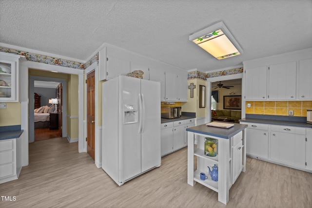 2000 Glissom St, Tarboro, NC 27886 - kitchen featuring white refrigerator with ice dispenser, dark countertops, light wood-style flooring, white cabinetry, and a textured ceiling