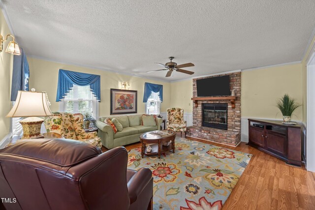 2000 Glissom St, Tarboro, NC 27886 - living room with a textured ceiling, light wood-type flooring, ceiling fan, a fireplace, and crown molding