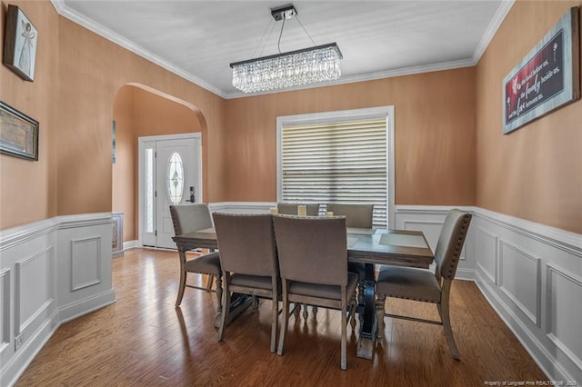 416 Kentucky Derby Ln, Lillington, NC 27546 - dining space with arched walkways, ornamental molding, a chandelier, a decorative wall, and wood finished floors