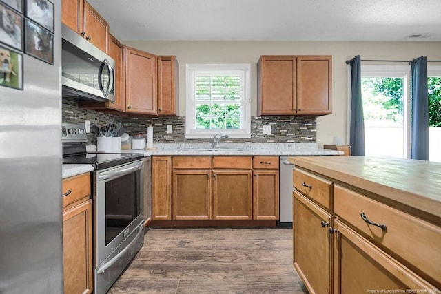 6582 Vineyard Dr, Fayetteville, NC 28304 - kitchen with stainless steel appliances, a sink, dark wood-type flooring, decorative backsplash, and brown cabinetry