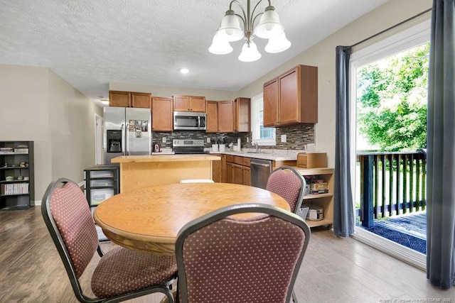 6582 Vineyard Dr, Fayetteville, NC 28304 - kitchen with appliances with stainless steel finishes, a chandelier, light countertops, wood finished floors, and a textured ceiling
