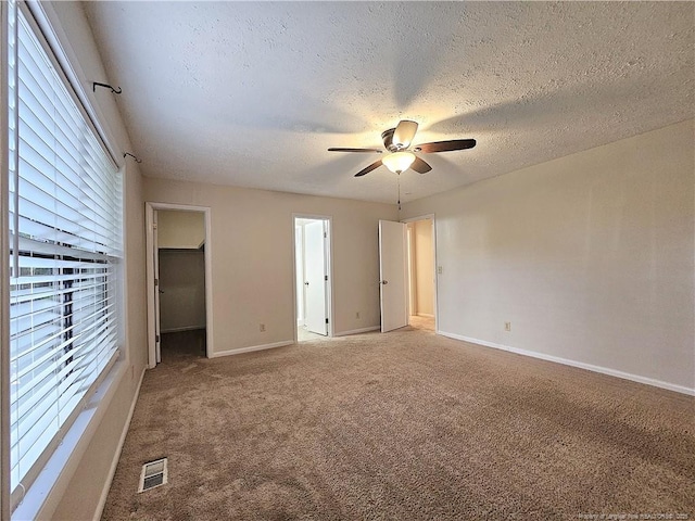 918 Dandridge Dr, Fayetteville, NC 28303 - unfurnished bedroom with carpet floors, a walk in closet, baseboards, a textured ceiling, and a ceiling fan